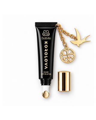 Korolova x BiaBelle Clear SPF 35 Lip Oil with the gold cap off and gold swallow charm