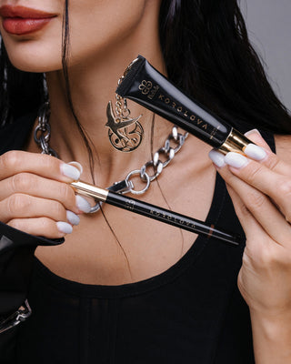 Korolova holding the Korolova x BiaBelle Clear SPF 35 Lip Oil with gold charm and the Lip Stain pen
